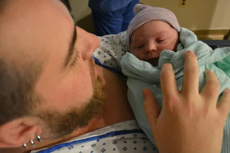 Kaci cradles his newborn baby. Photo: SWNS Kaci cradles his newborn baby. Photo: SWNS