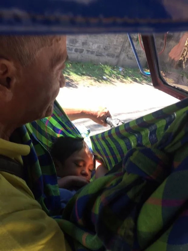 Father cradles toddler while working as tricycle driver Father cradles toddler while working as tricycle driver