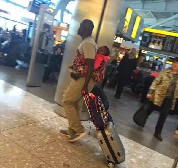 This proud dad doesn't mind at all carrying his baby at a busy airport This proud dad doesn't mind at all carrying his baby at a busy airport