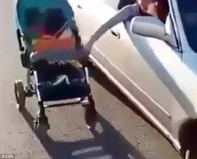 Reckless mother pushing her son in a baby buggy while driving Reckless mother pushing her son in a baby buggy while driving