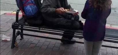 Adorable young girl shares her dinner with homeless man outside restaurant